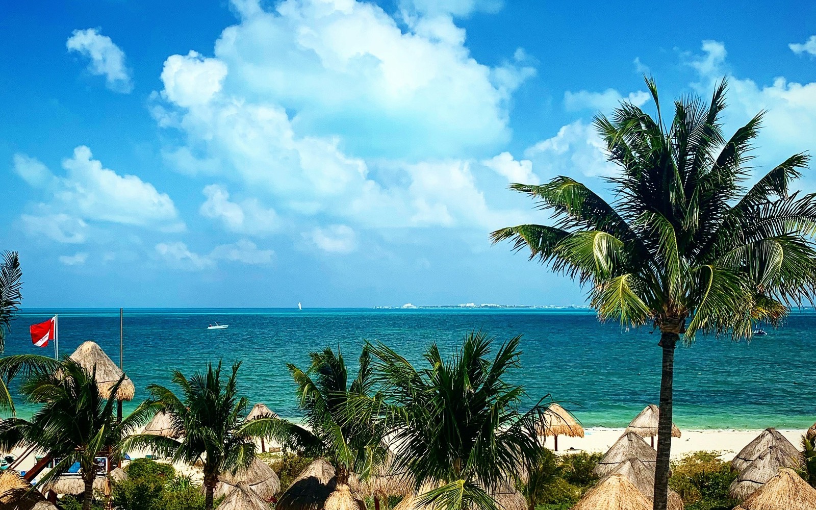 Pláž so slamenými slnečníkmi a palmami na ostrove Isla Mujeres