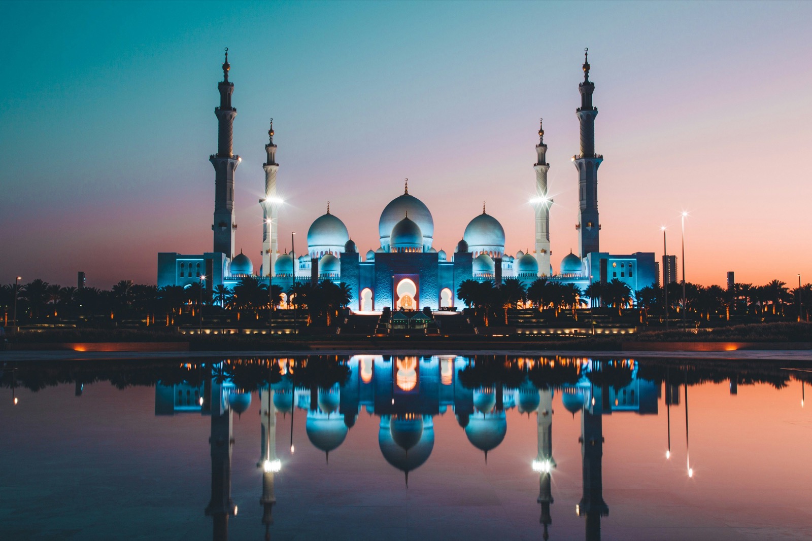 Mešita šejka Zayeda v Abu Dhabi osvetlená za súmraku s odrazom vo vode