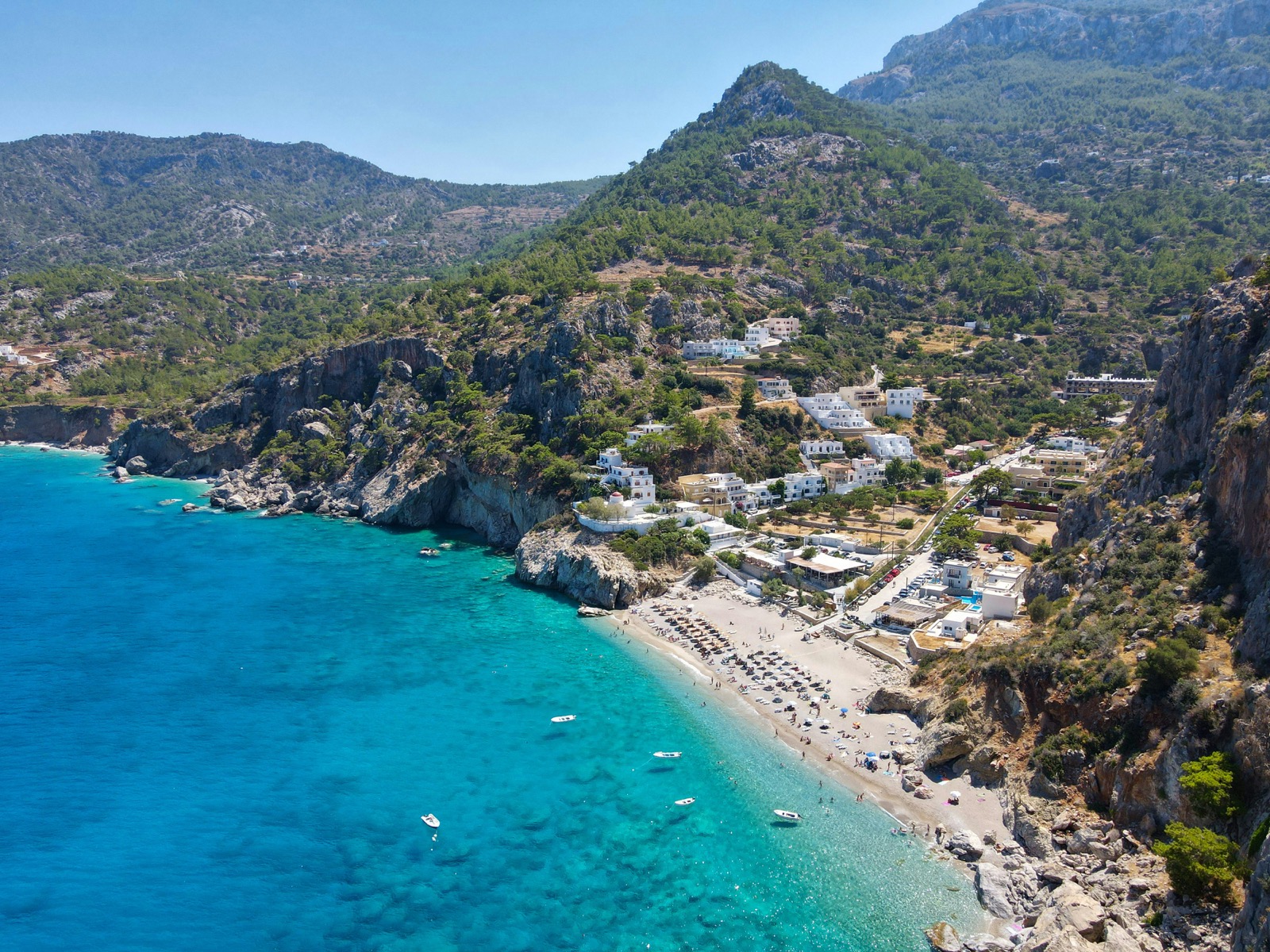 Pobrežie s tyrkysovým morom a dedinou pri pláži na ostrove Karpathos