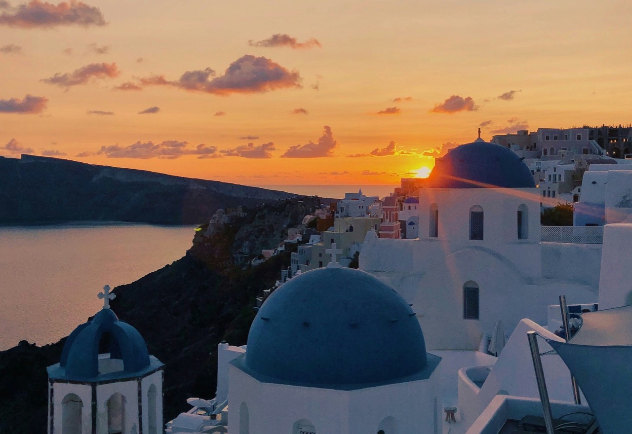 Západ slnka nad modrými kupolami kostolov v meste Oia na Santorini
