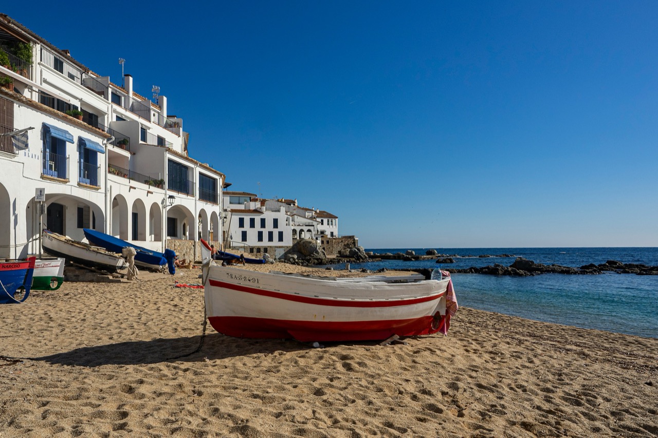 Biele domy a člny na pláži v Calelle de Palafrugell na Costa Brava