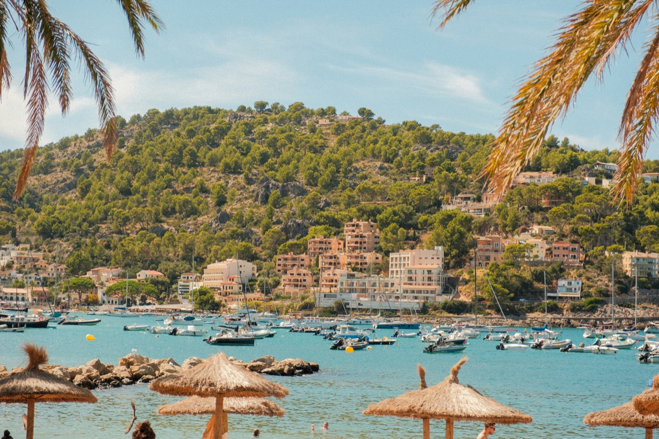 Záliv Port de Sóller so slamenými slnečníkmi a loďami