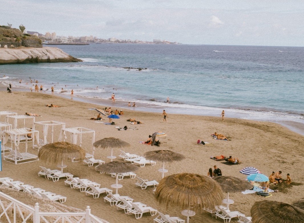 Pláž Playa del Duque v Costa Adeje so slamenými slnečníkmi a ležadlami